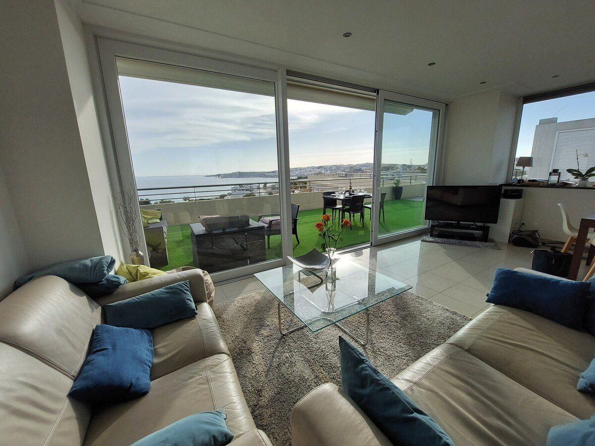 Living room with sofas, TV, and view through to the dining area and terrace