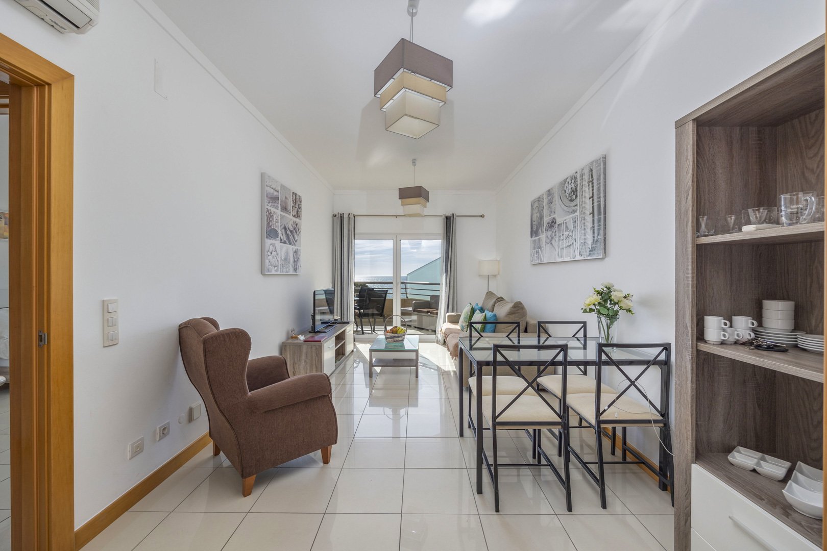 Living and dining area with dining table, shelving unit, and balcony view