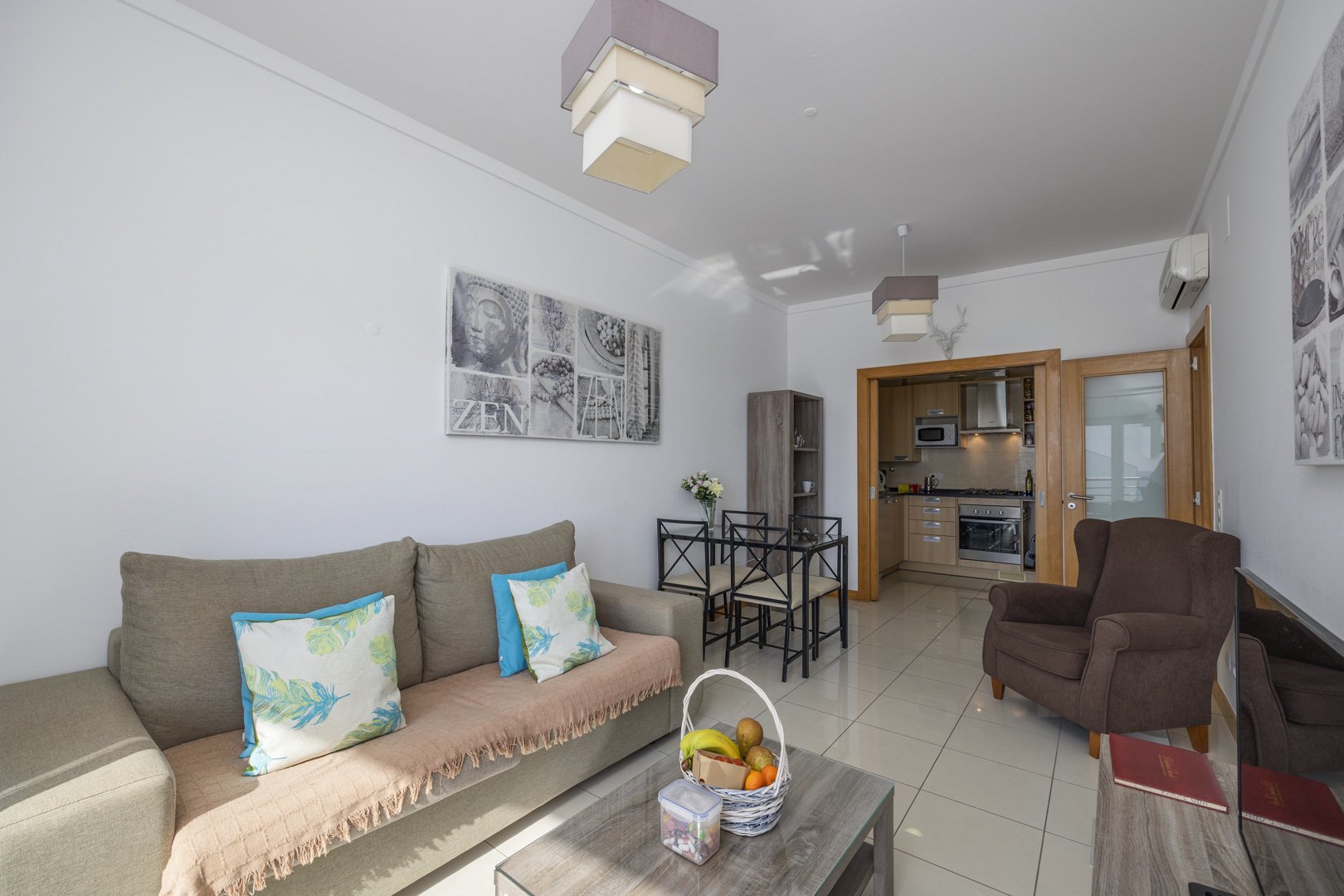 Living room with sofa, armchair, and view through to the kitchen