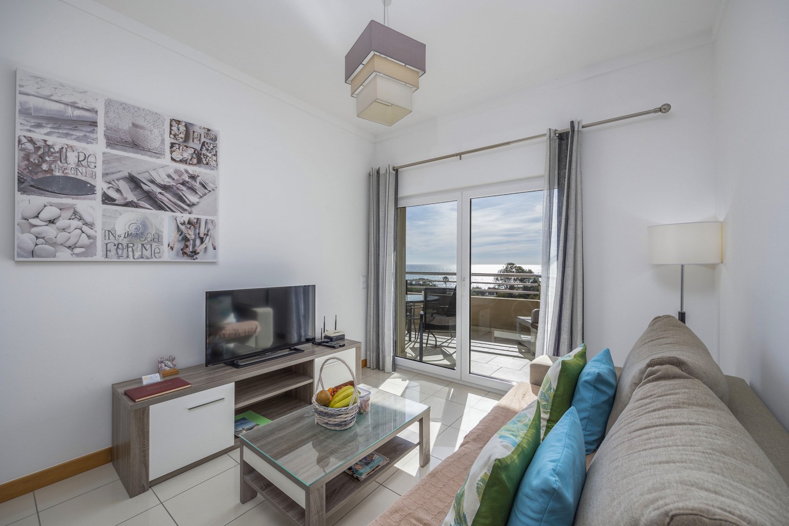 Living room with sofa, TV, and balcony access