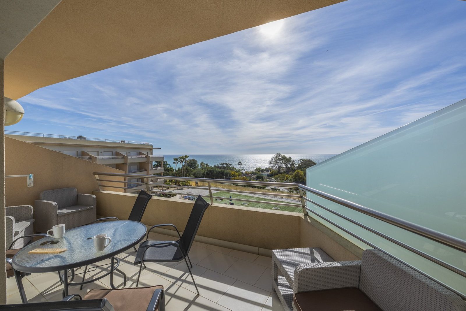 Balcony with table and chairs overlooking the pool and coastline