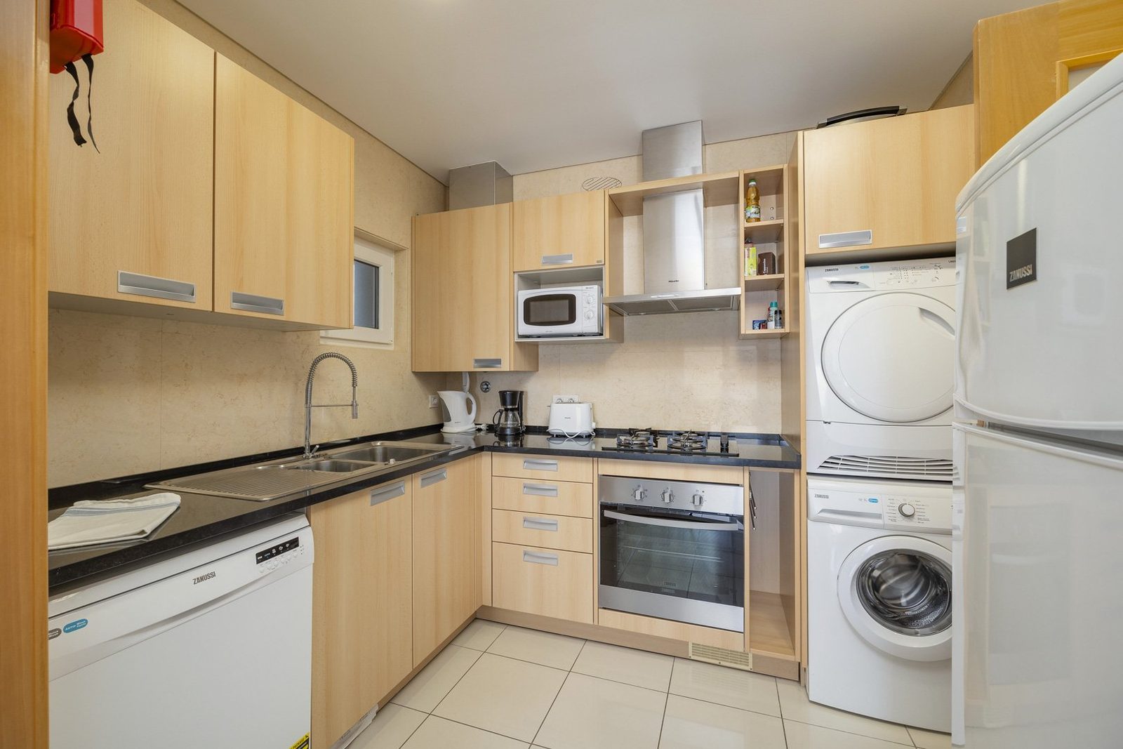 Kitchen with stacked washer-dryer, oven, and dishwasher