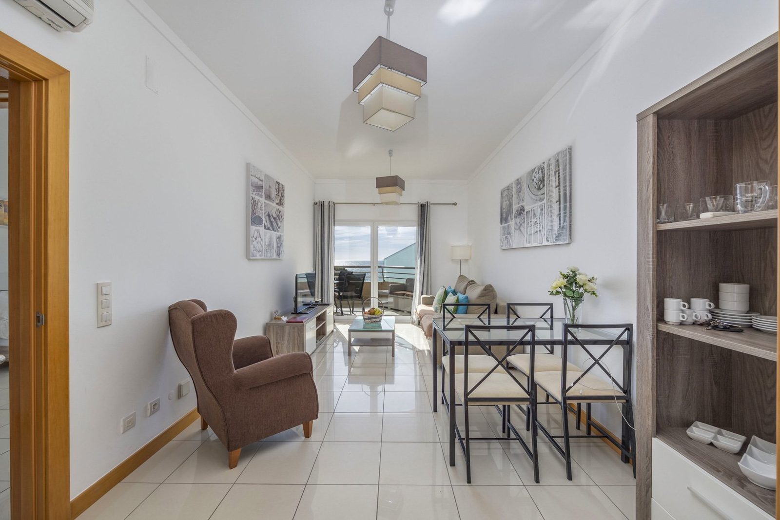 Living and dining area with dining table, shelving unit, and balcony view