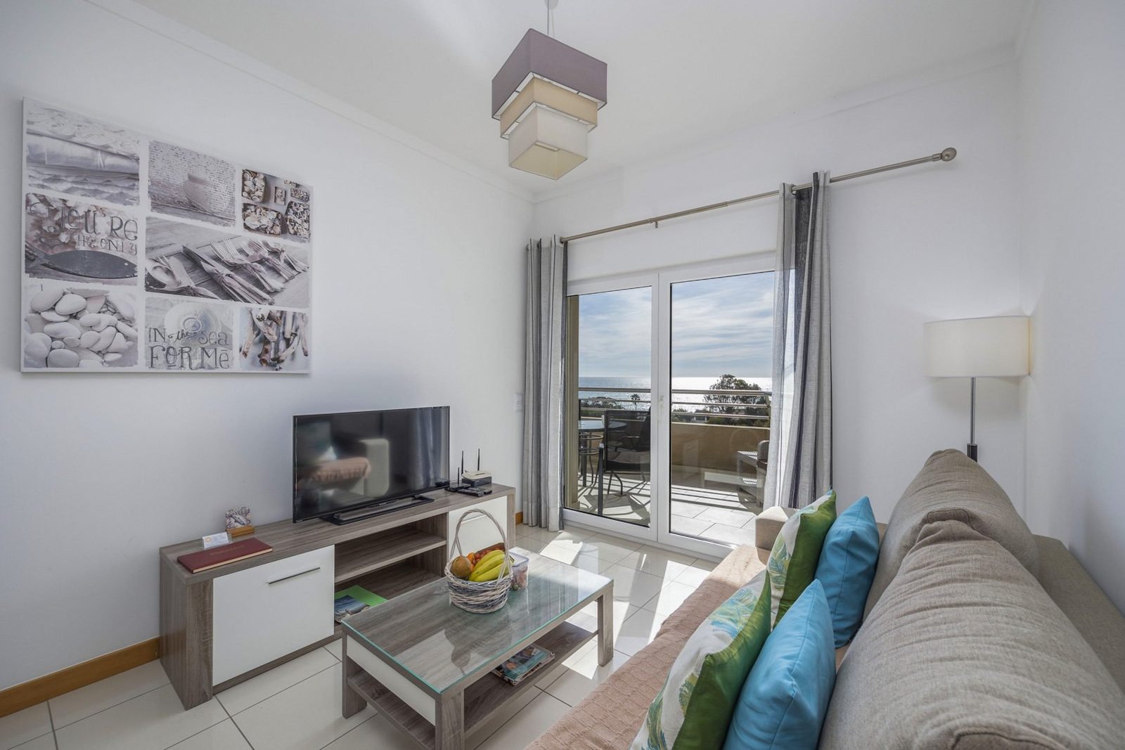 Living room with sofa, TV, and balcony access