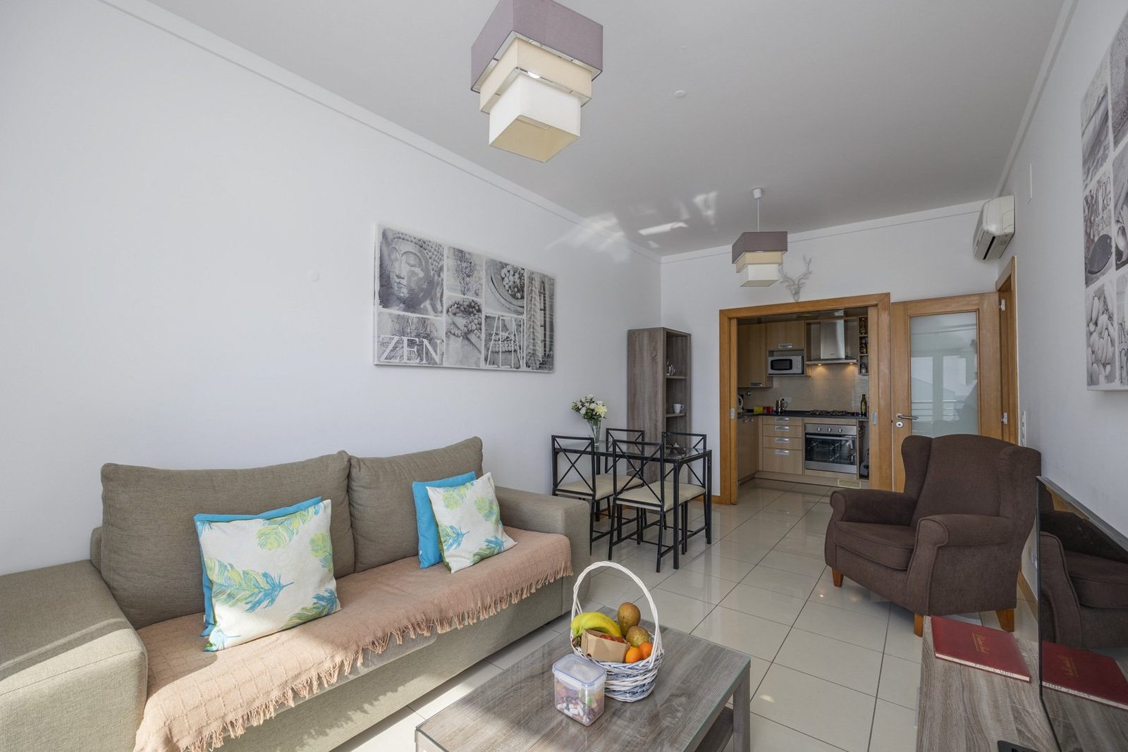 Living room with sofa, armchair, and view through to the kitchen