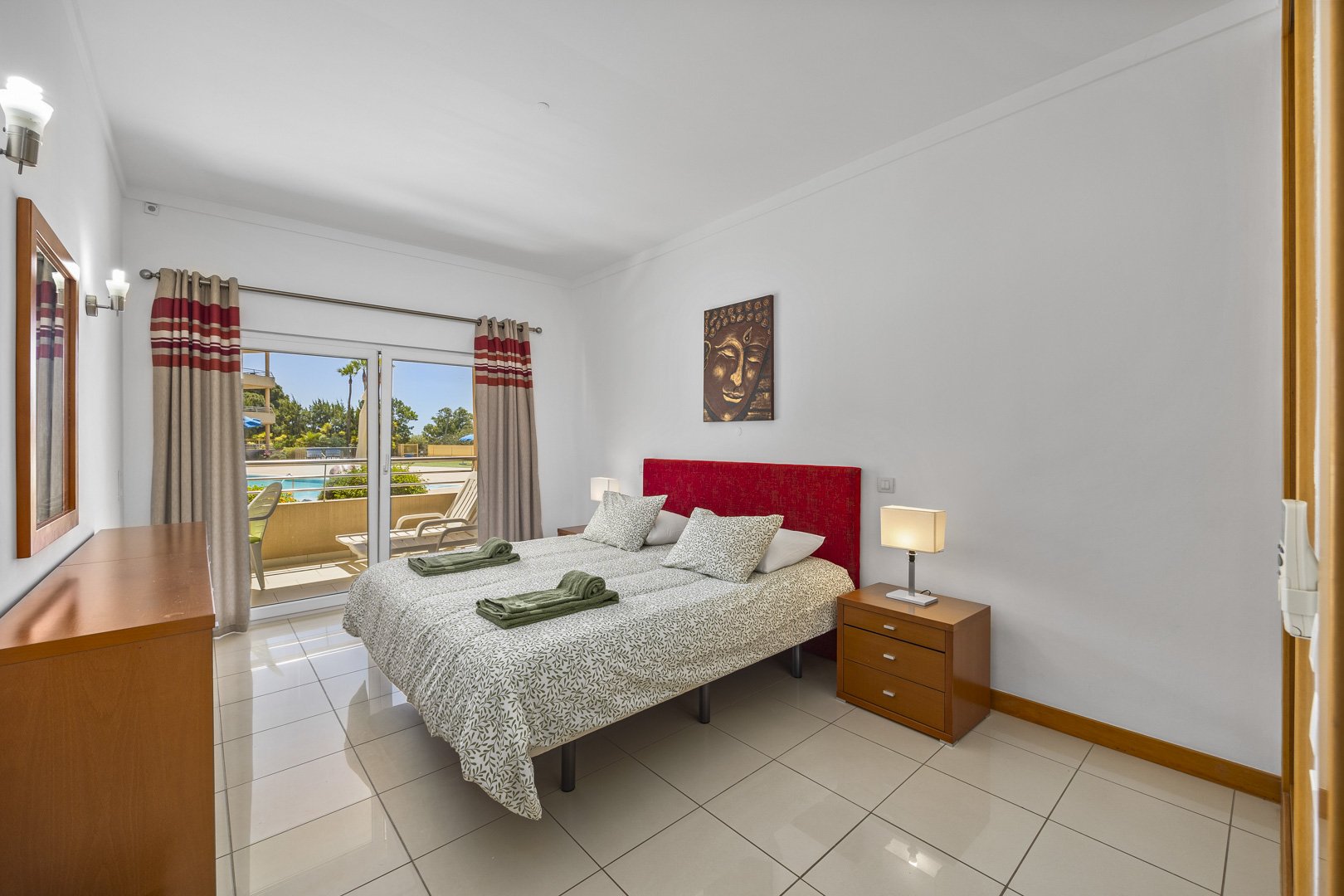 Bedroom with red upholstered headboard, pool view, and terrace access