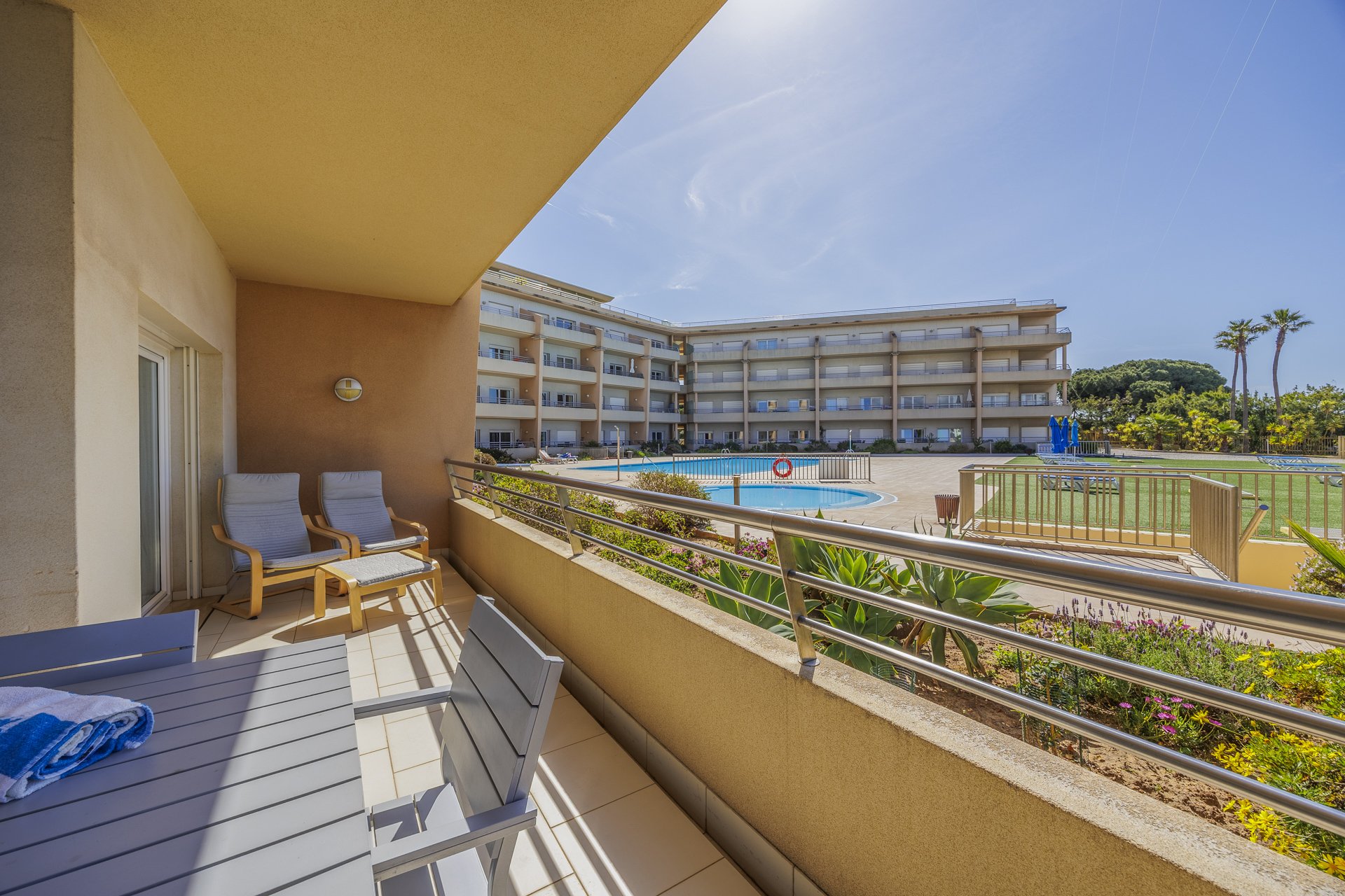 Balcony with lounge chairs and a view over the pool and building