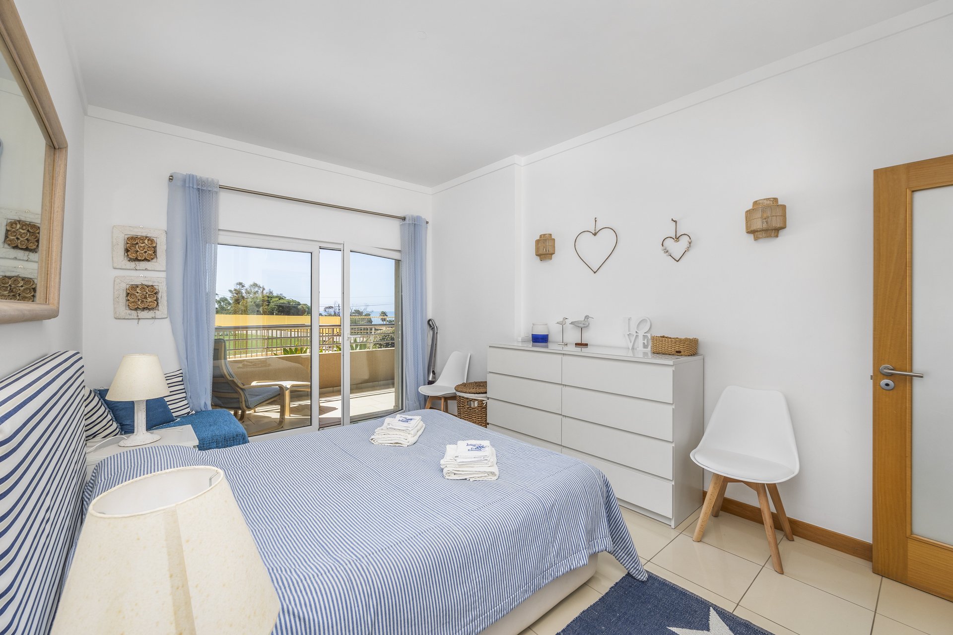 Bedroom with chest of drawers, armchair, and balcony access
