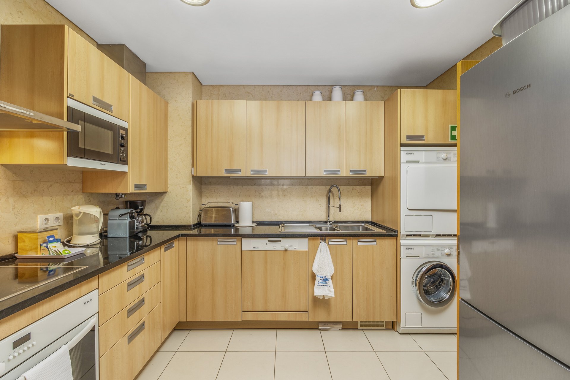 Kitchen with fridge, dishwasher, and stacked washer-dryer