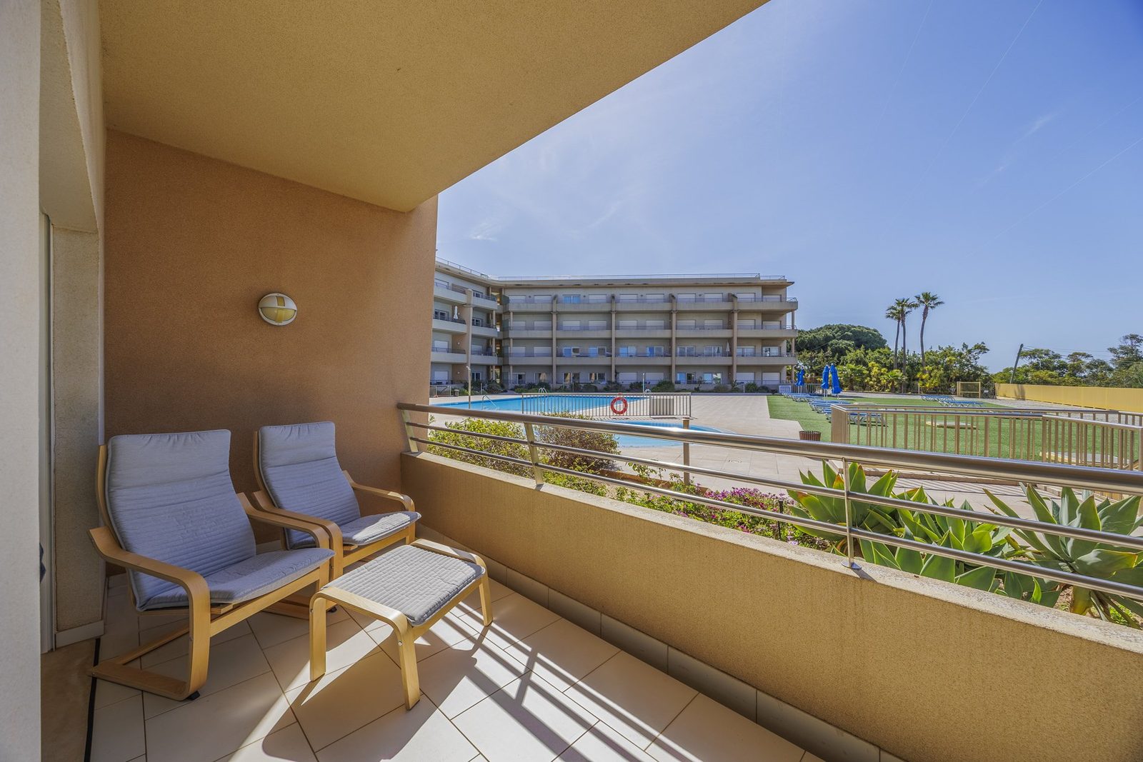 Balcony with lounge chairs, footstool, and pool view