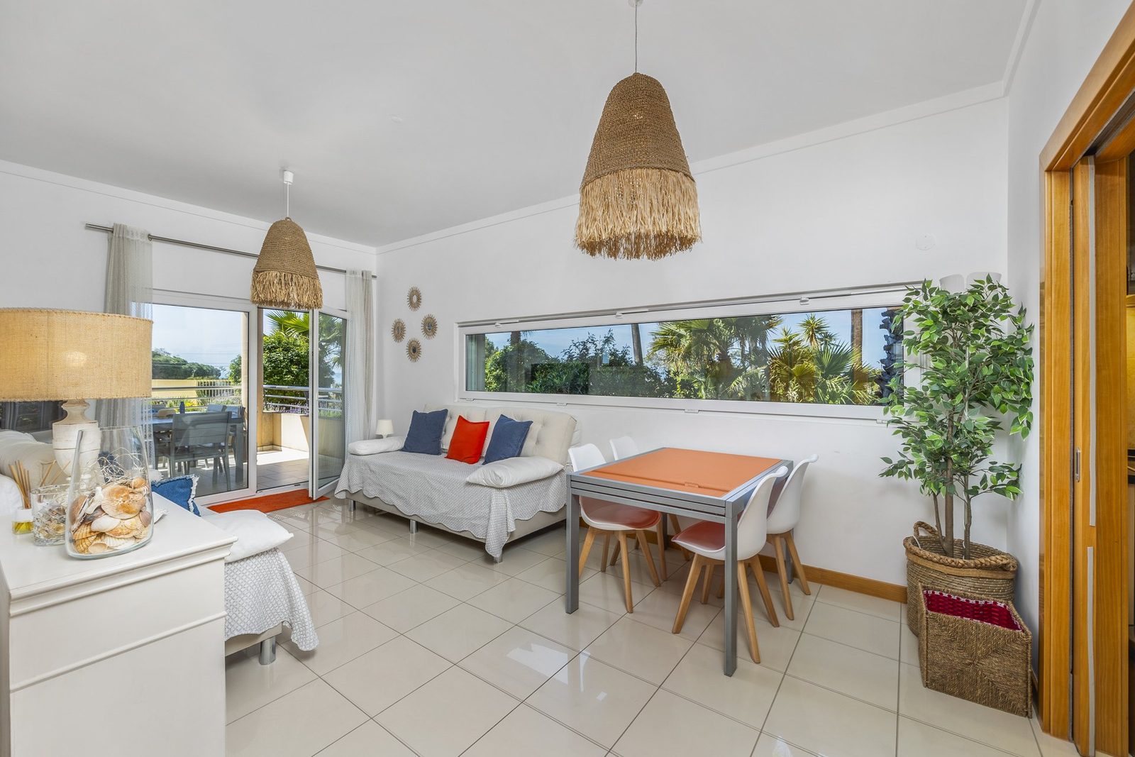Living and dining area with sofa, dining table, and balcony access