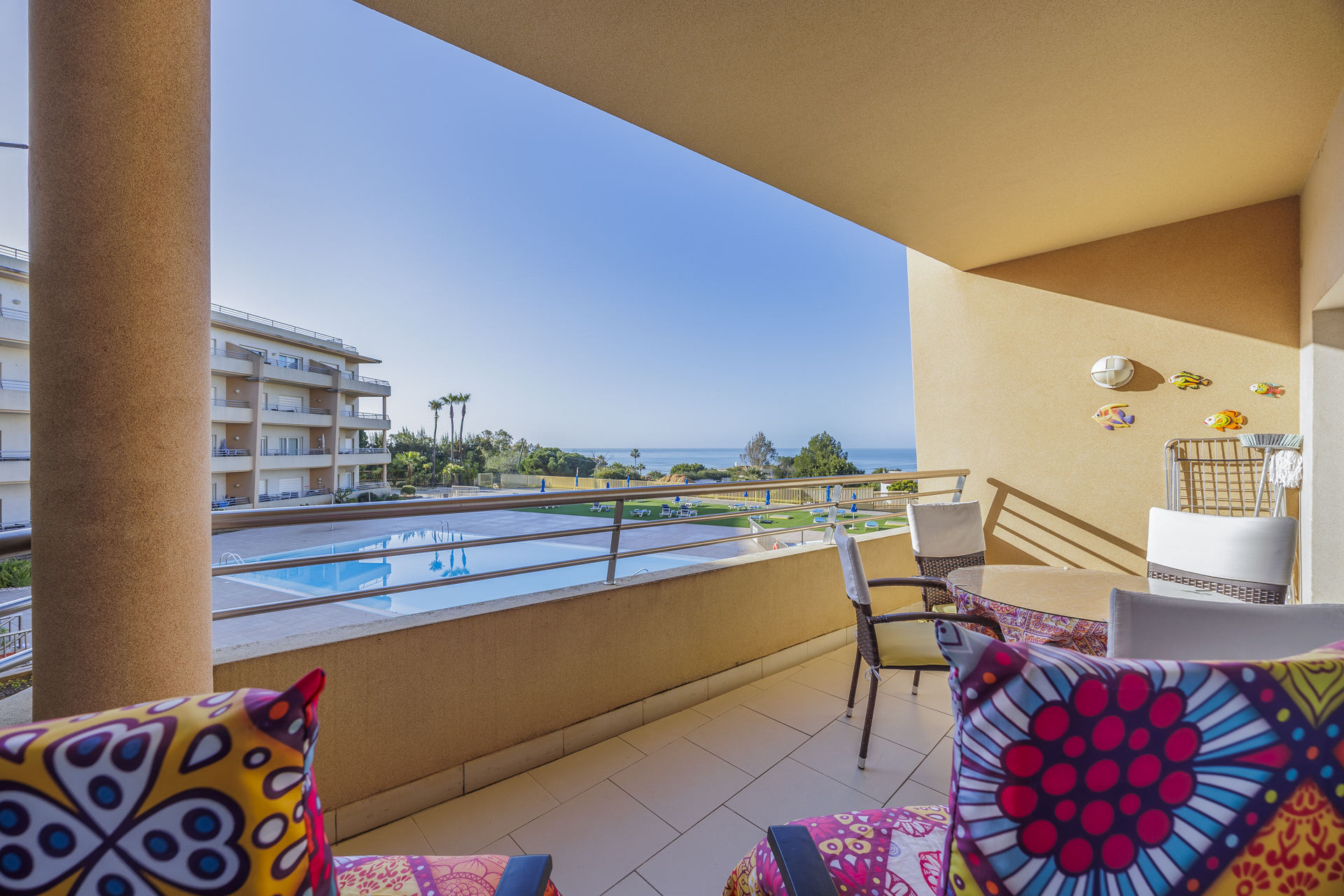 Balcony with dining table, chairs, and sea view over the pool and gardens