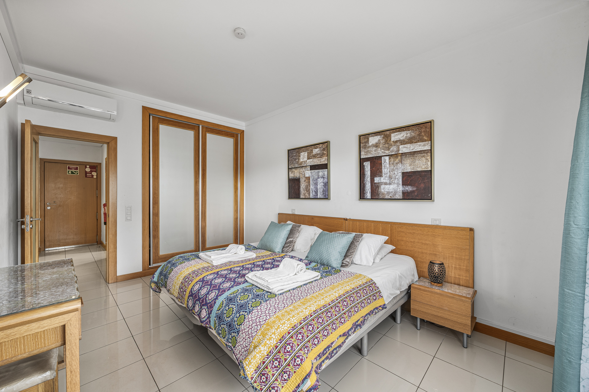 Bedroom with double bed, sliding wardrobe doors, and air conditioning unit