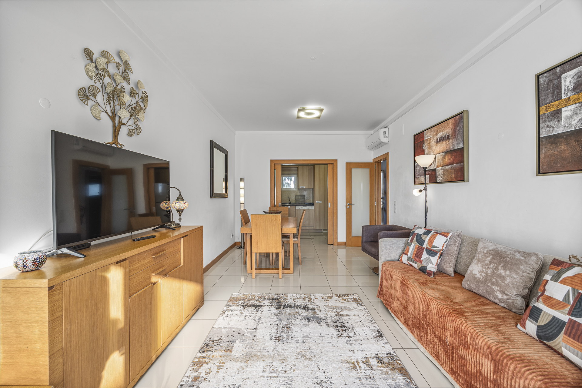 Living room with sofa, TV, and view through to the dining area and hallway