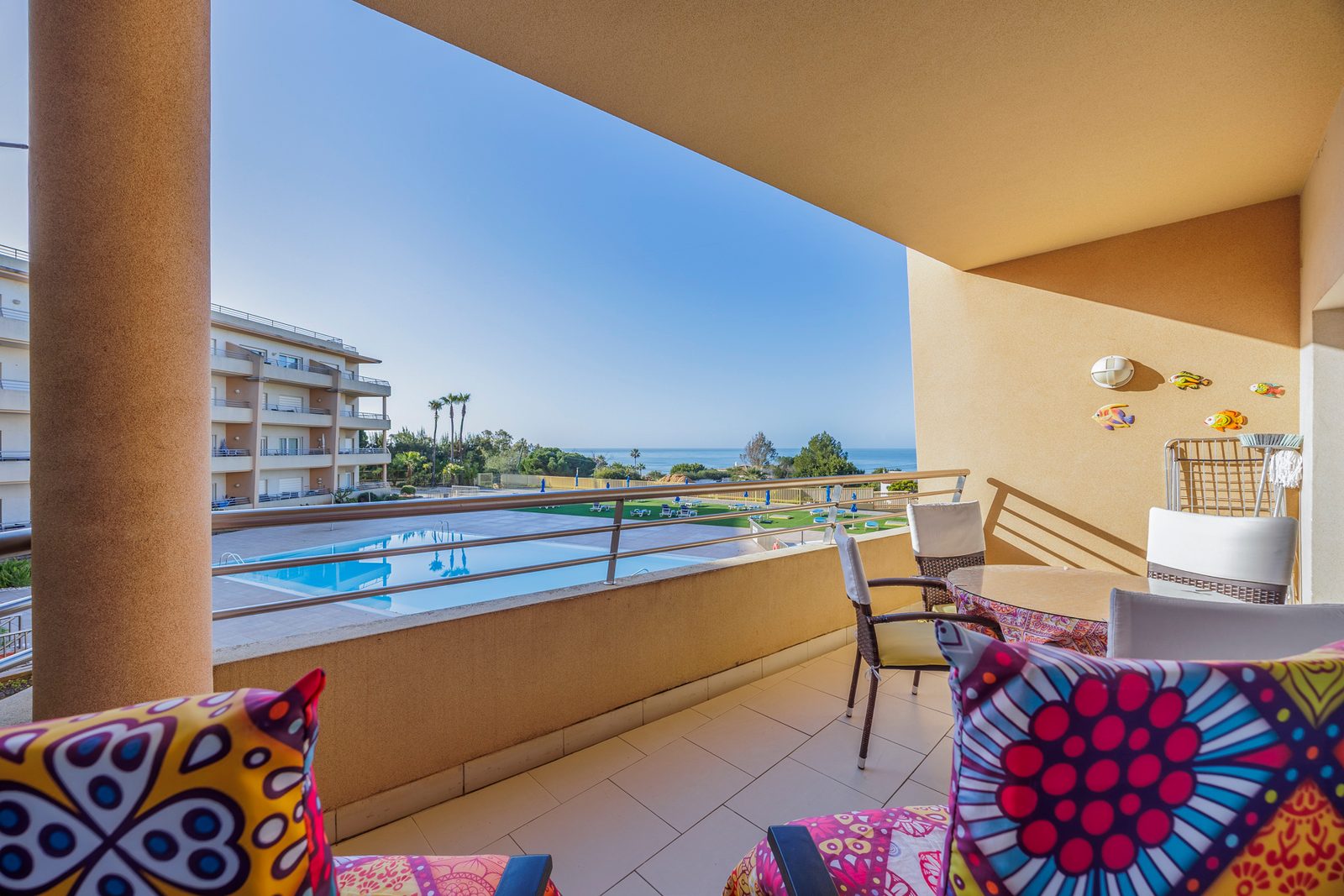 Balcony with dining table, chairs, and sea view over the pool and gardens