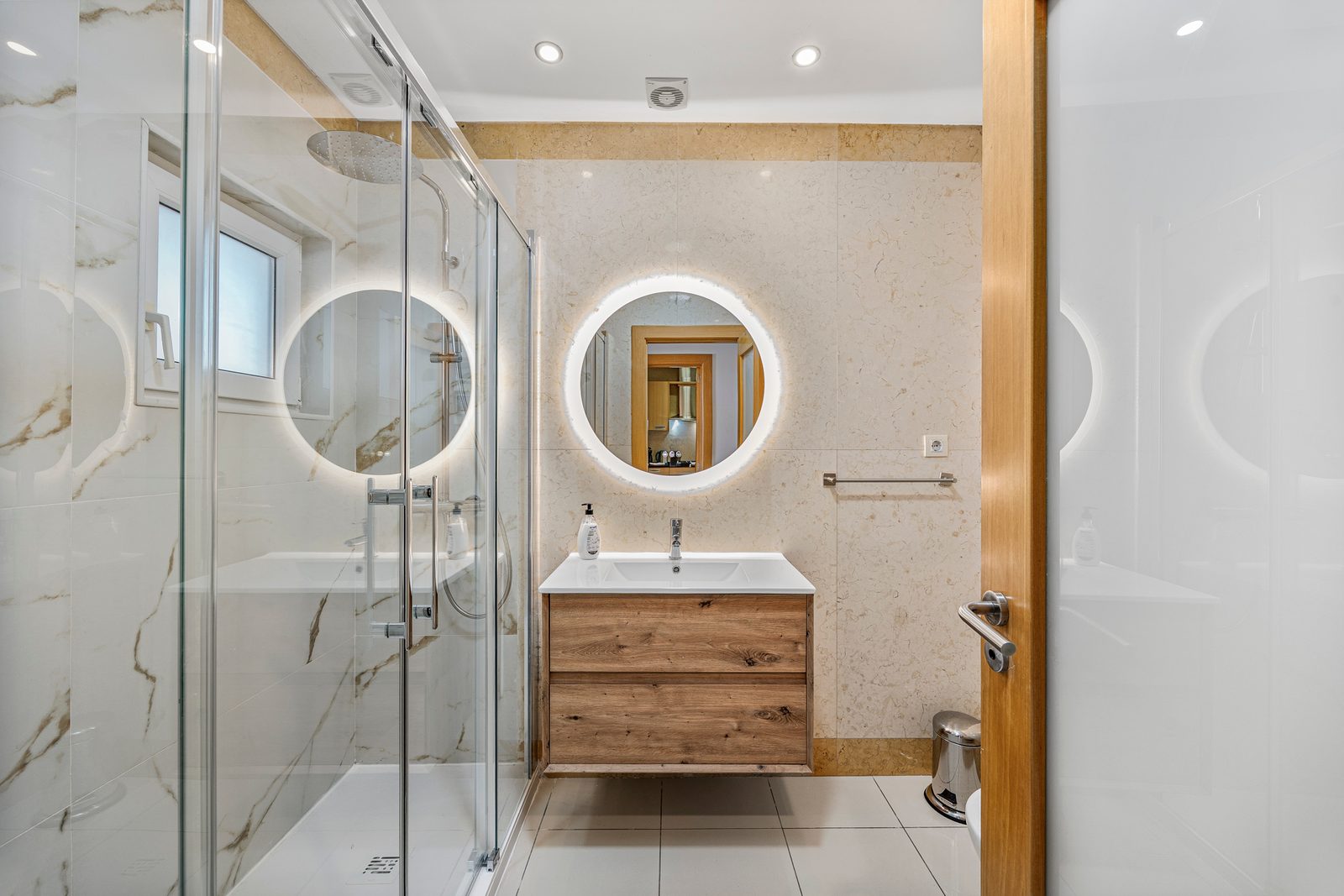 Bathroom with walk-in shower, illuminated mirror, and marble-effect vanity