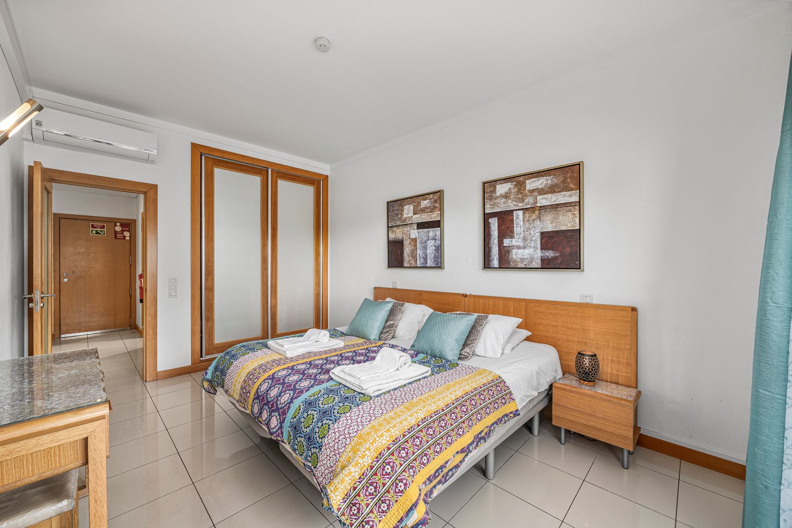 Bedroom with double bed, sliding wardrobe doors, and air conditioning unit