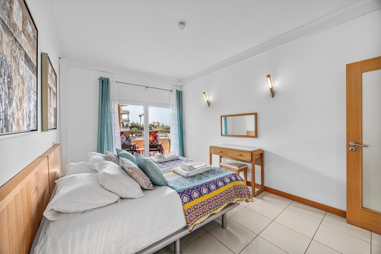 Bedroom with double bed and a view through the window towards the balcony