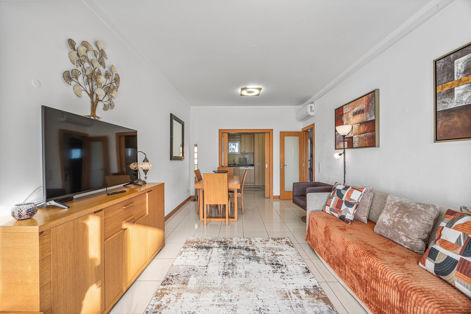 Living room with sofa, TV, and view through to the dining area and hallway
