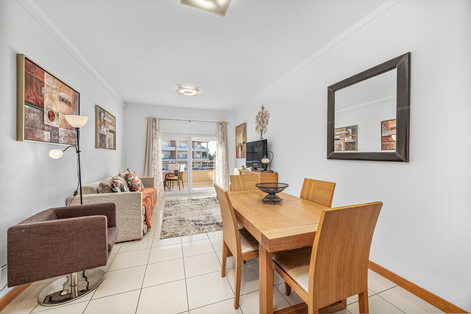 Living room with armchair, sofa, and dining table beyond