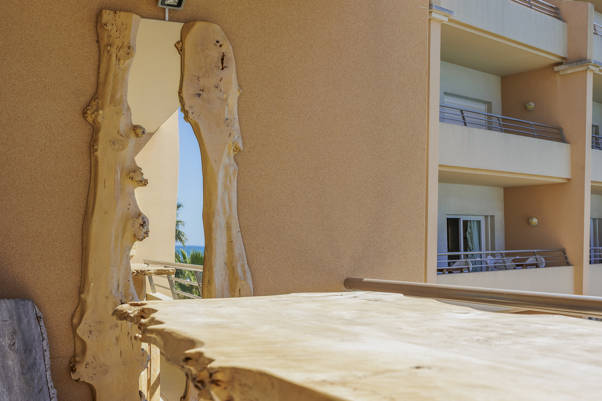 Close-up of the balcony's live-edge wooden table against the building view