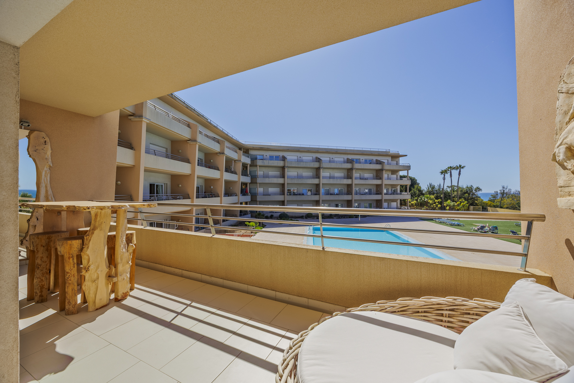 Balcony with a live-edge wooden table and pool view