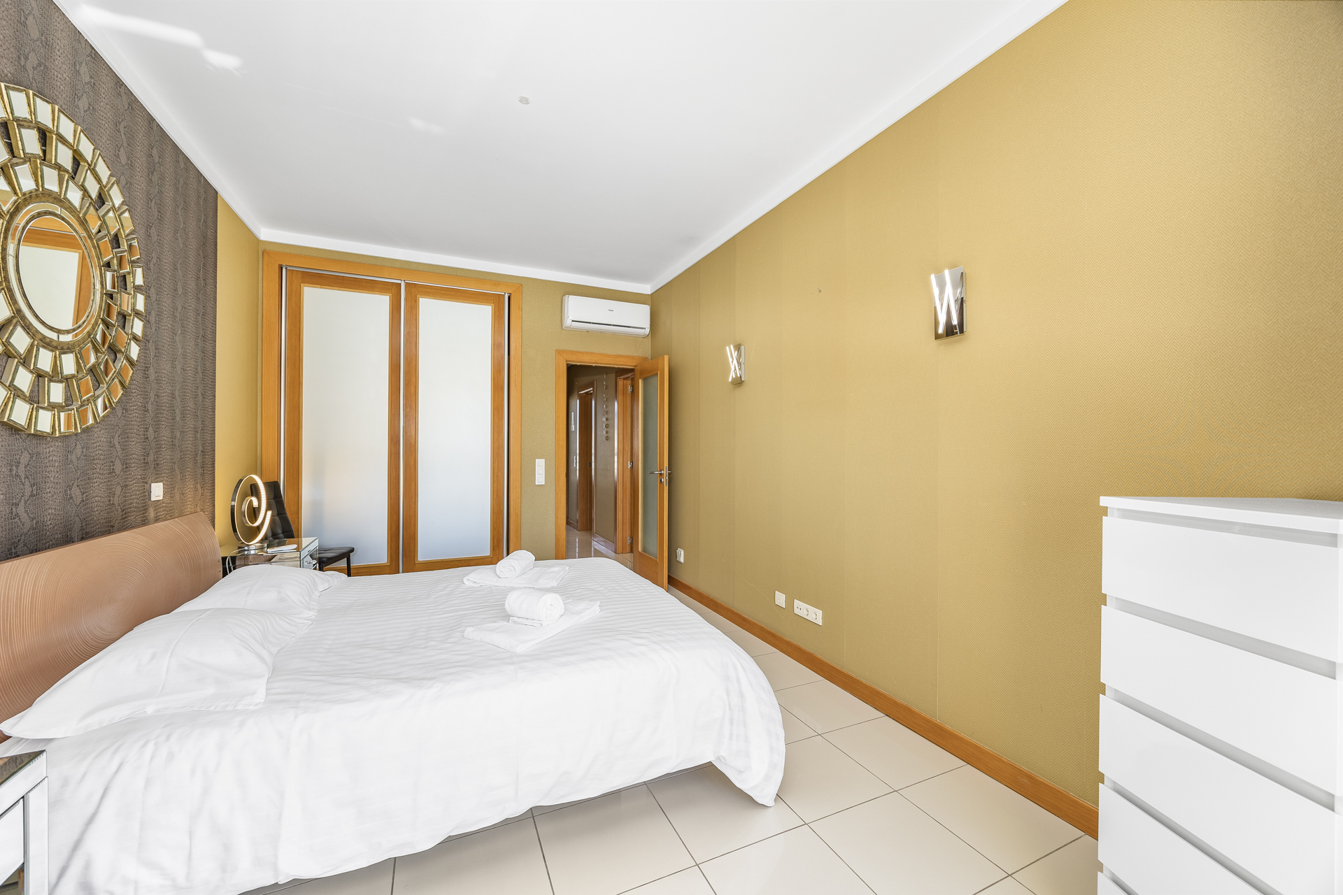 Bedroom with double bed, decorative mirror, and fitted wardrobe