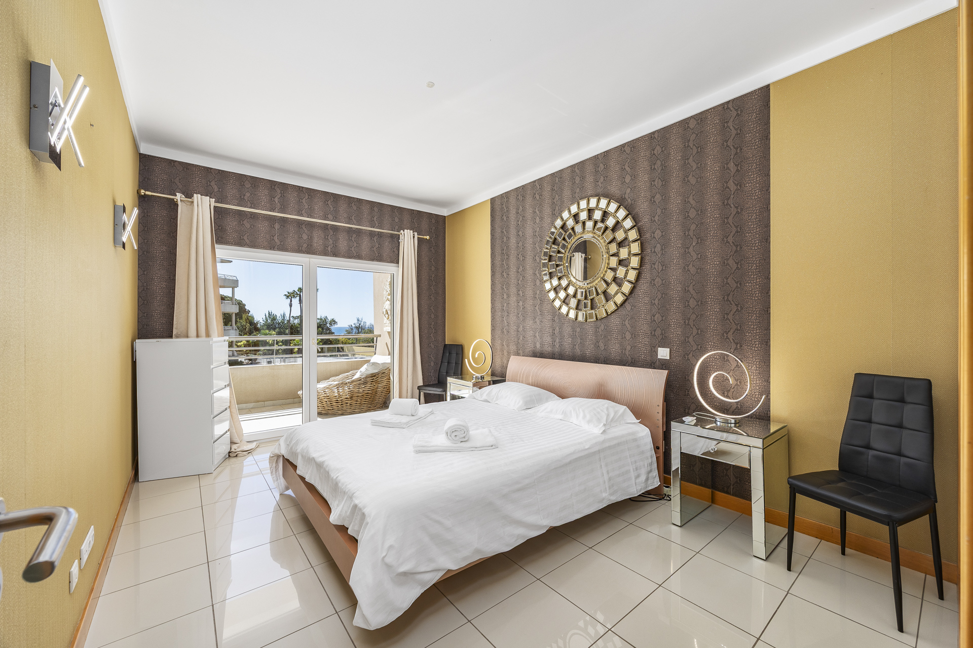 Bedroom with double bed, patterned feature wall, and desk chair