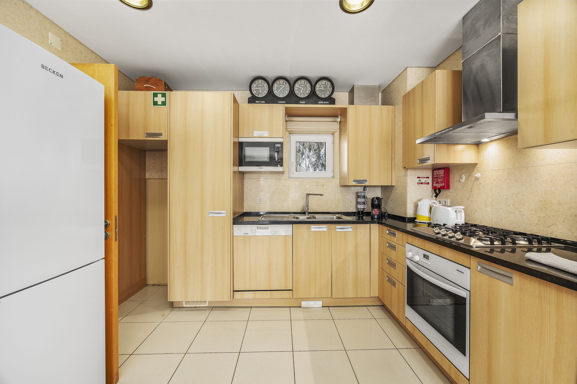 Kitchen with fridge-freezer, microwave, and decorative wall clocks