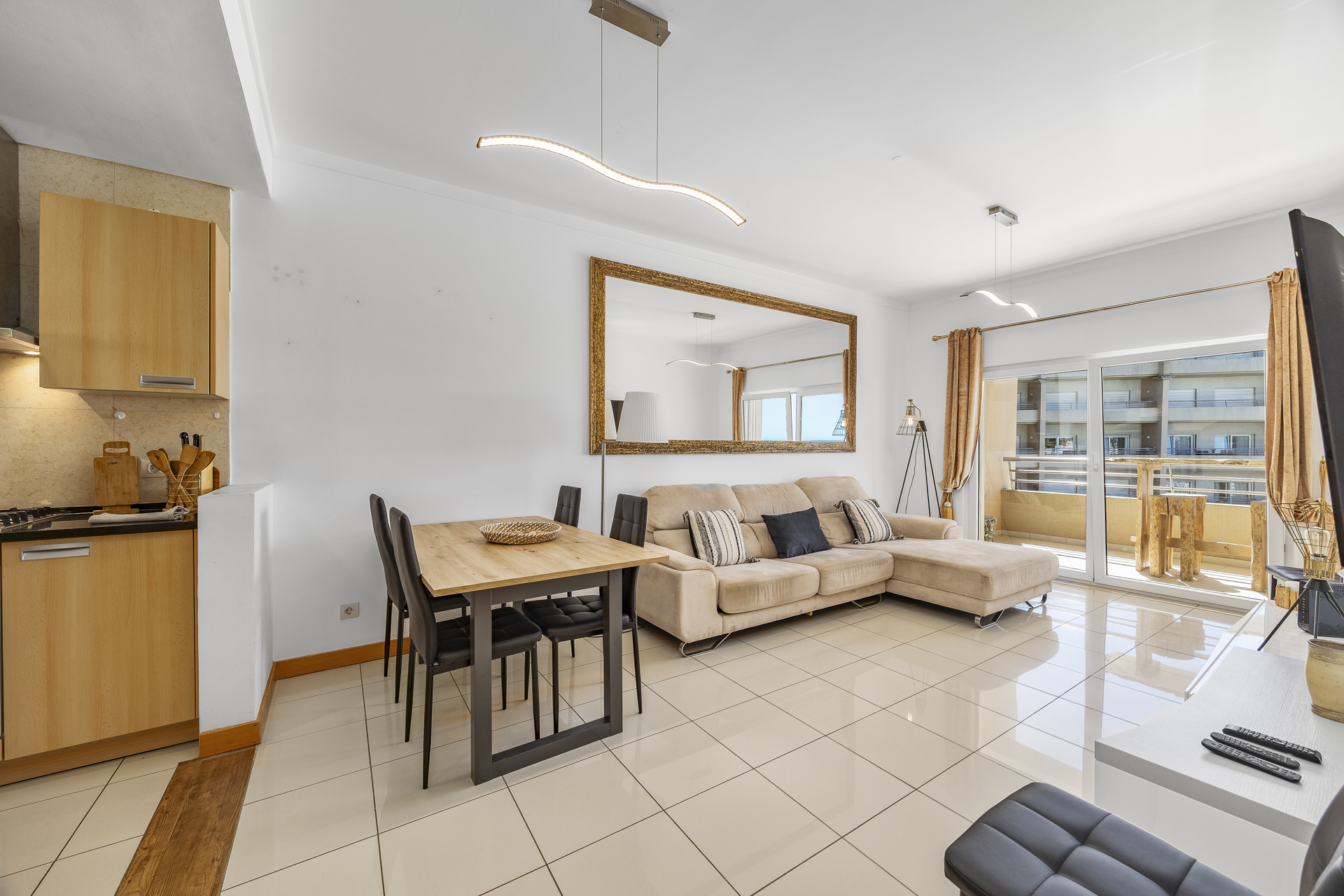 Open-plan living and dining area with sofa, dining table, and balcony access