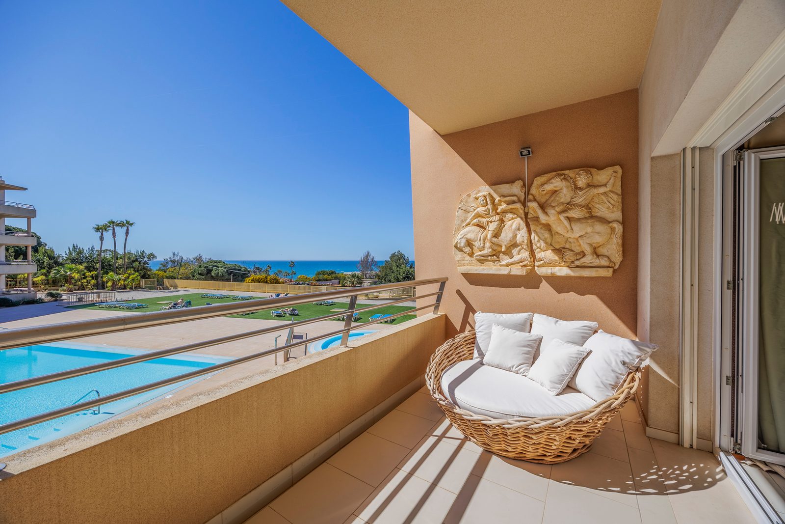 Balcony with a wicker lounge chair and sea view