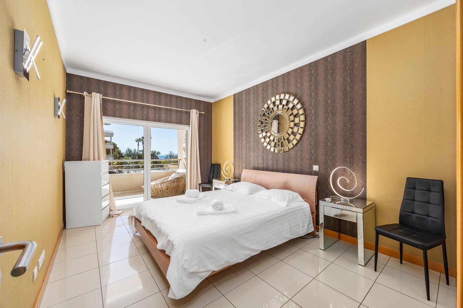 Bedroom with double bed, patterned feature wall, and desk chair