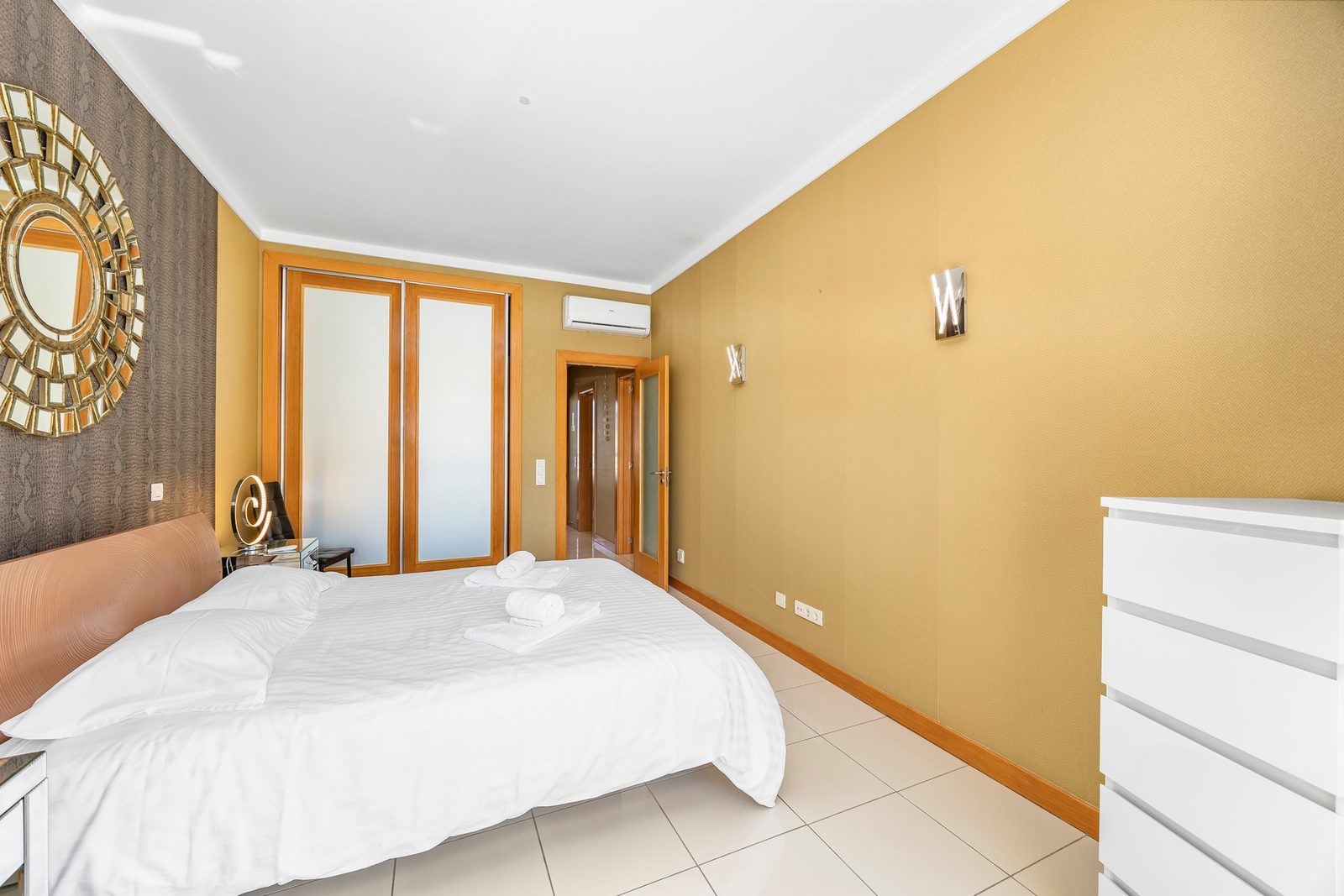 Bedroom with double bed, decorative mirror, and fitted wardrobe