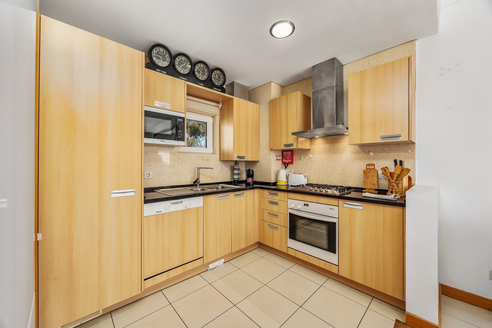 Kitchen with gas hob, extractor hood, and fitted wooden cabinetry
