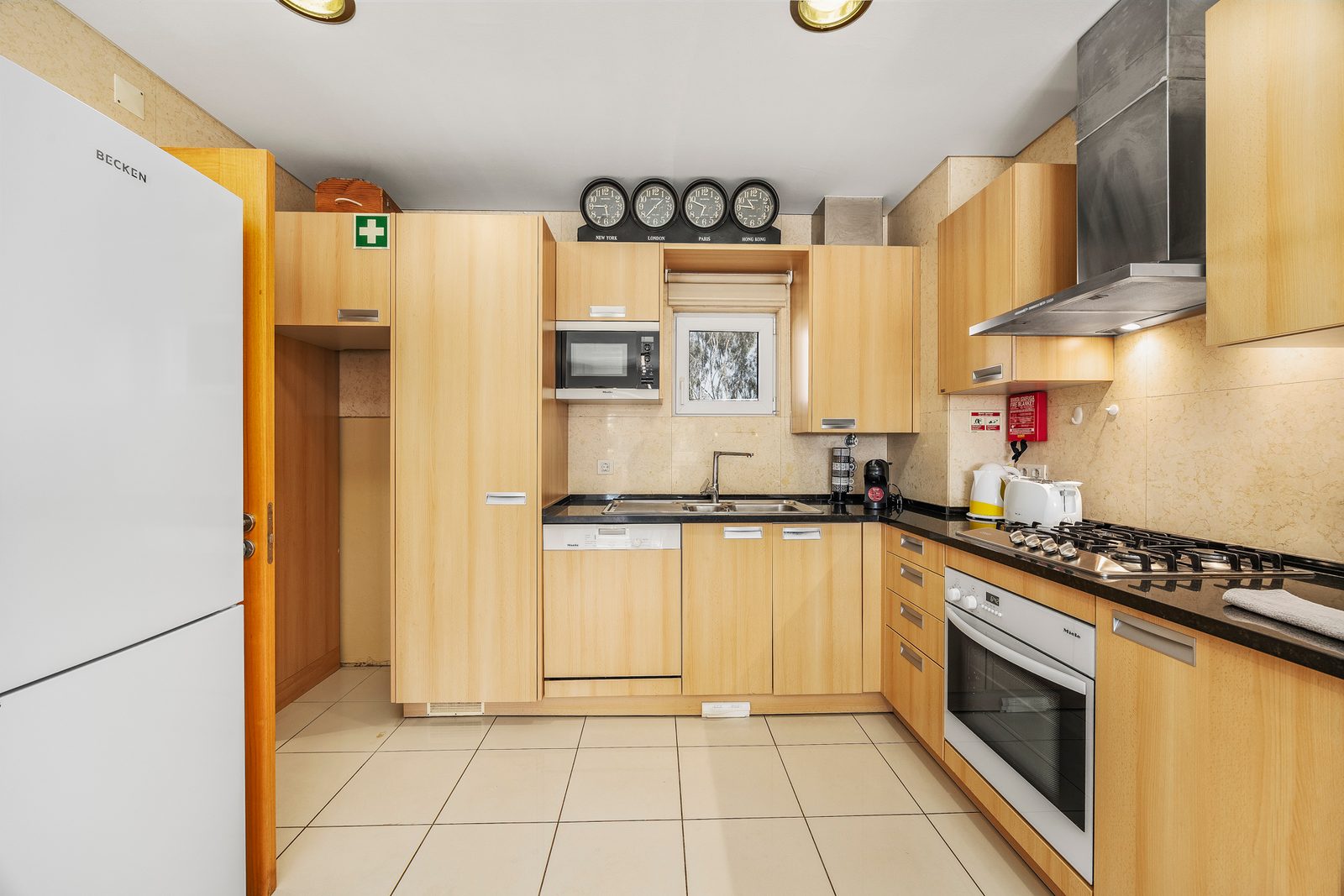 Kitchen with fridge-freezer, microwave, and decorative wall clocks