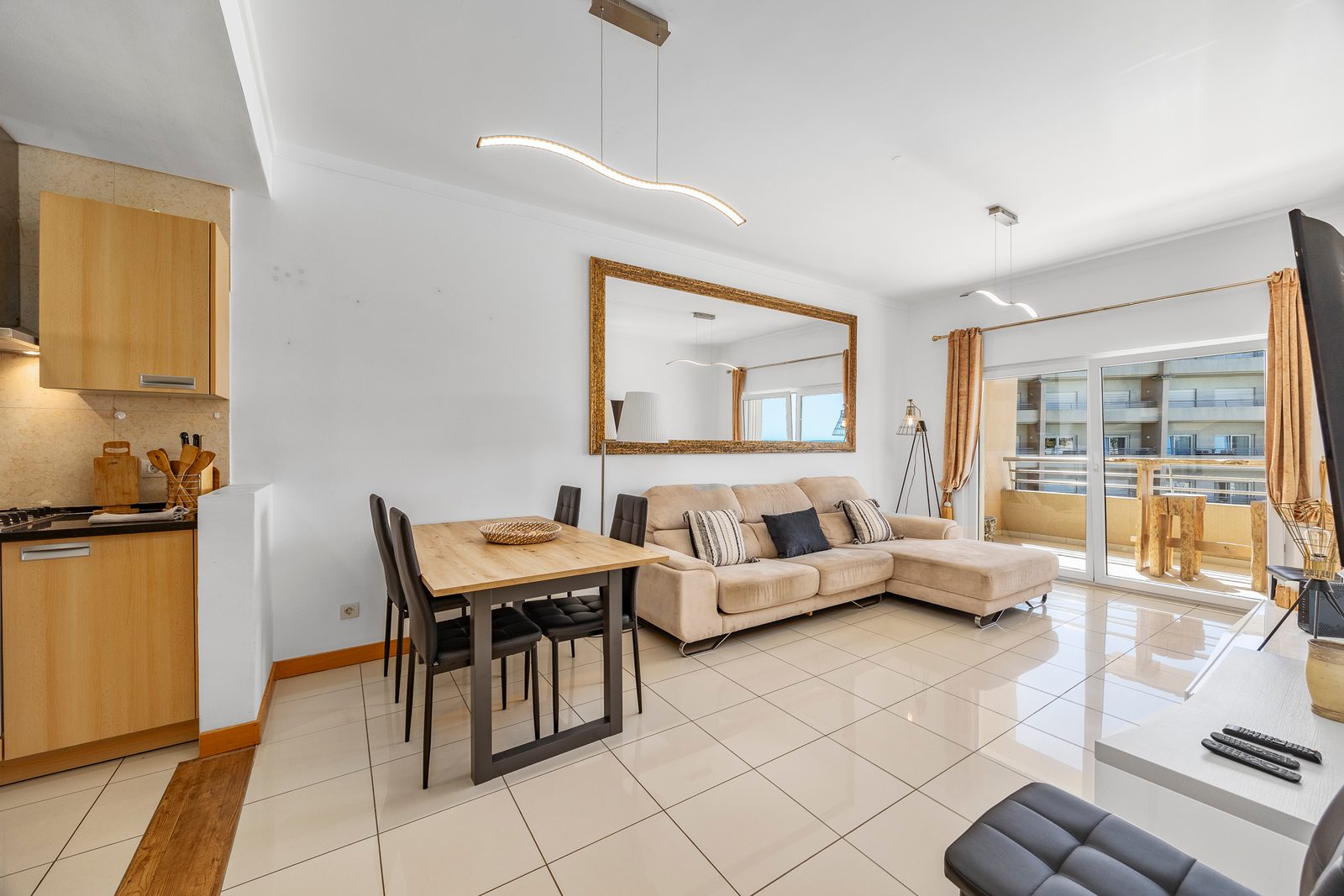 Open-plan living and dining area with sofa, dining table, and balcony access