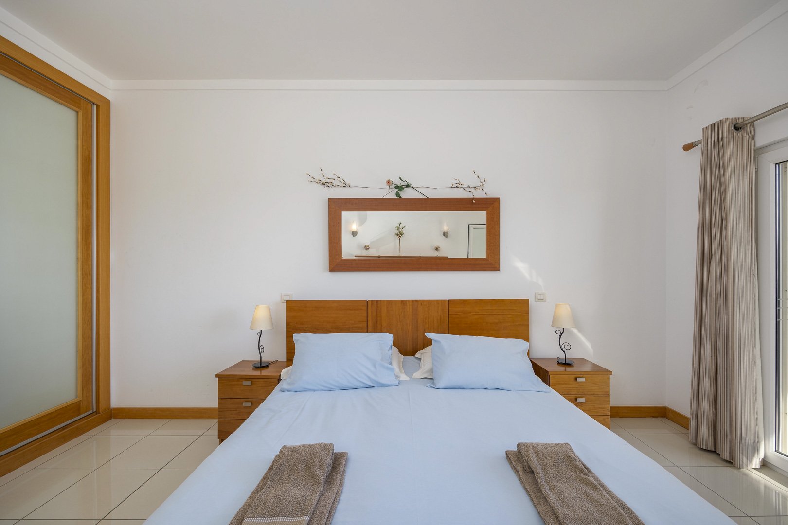 Bedroom with wooden headboard and mirror above