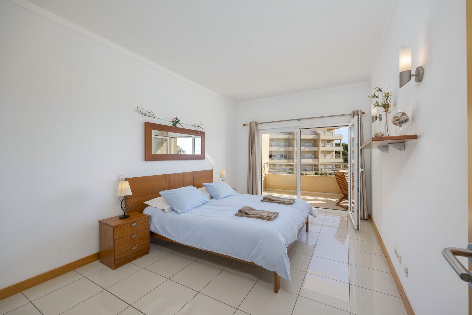 Bedroom with wooden headboard, mirror, and balcony access