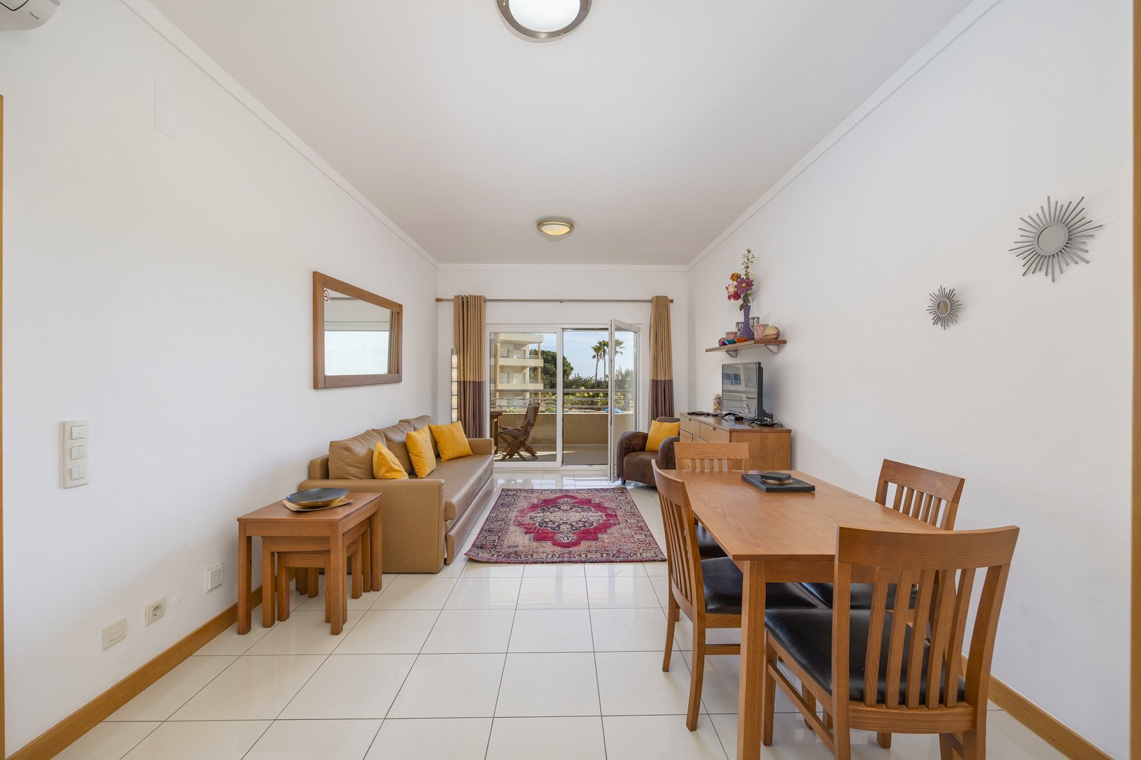 Living and dining area with sofa, dining table, and balcony access