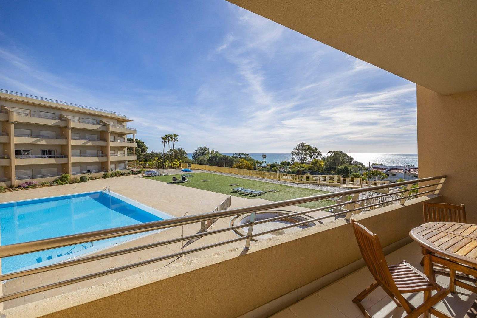 Balcony with table and chairs, overlooking the pool and sea