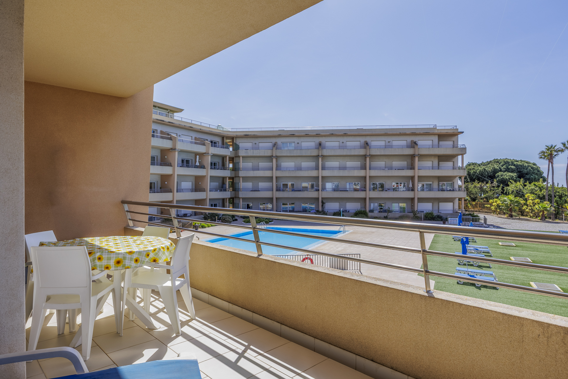 Balcony with dining table and view over the lawn and pool