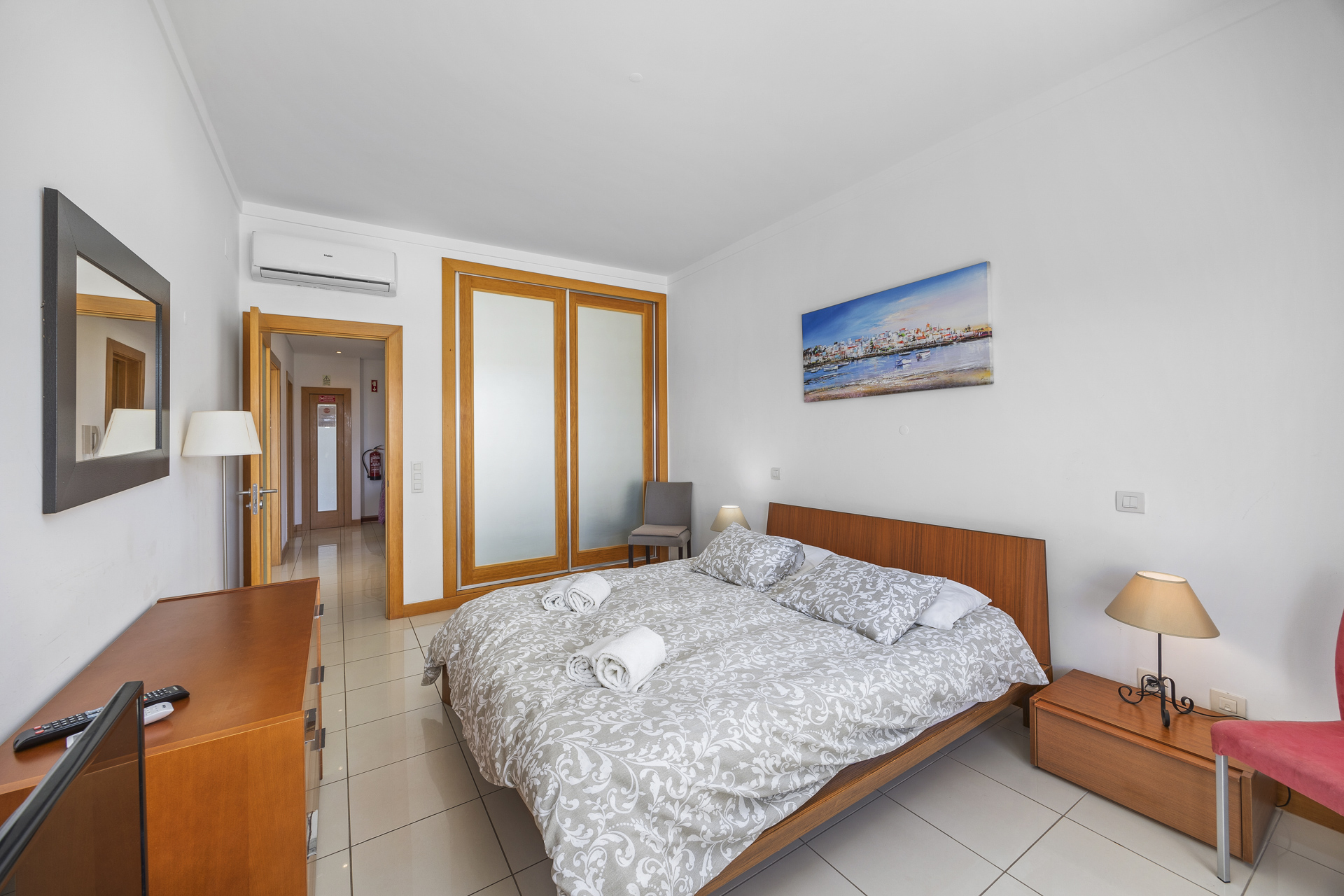 Bedroom with wall-mounted air conditioning and frosted glass wardrobe doors