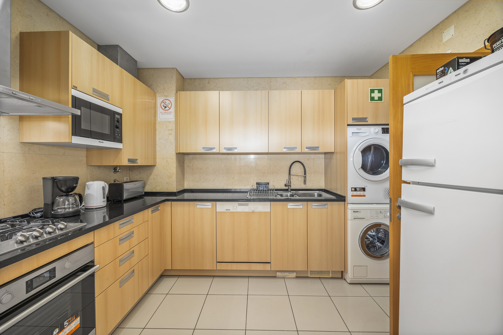 Kitchen with dishwasher, fridge, and stacked washer-dryer