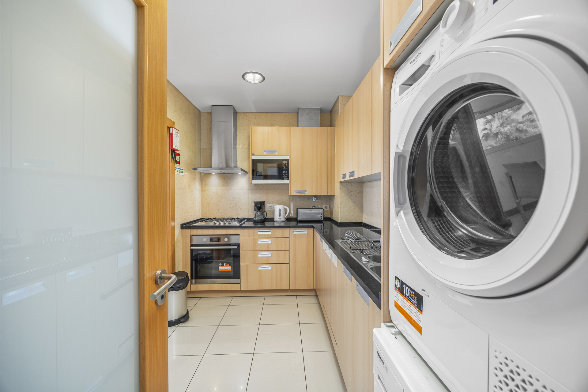 Kitchen with gas hob, oven, and stacked washer-dryer