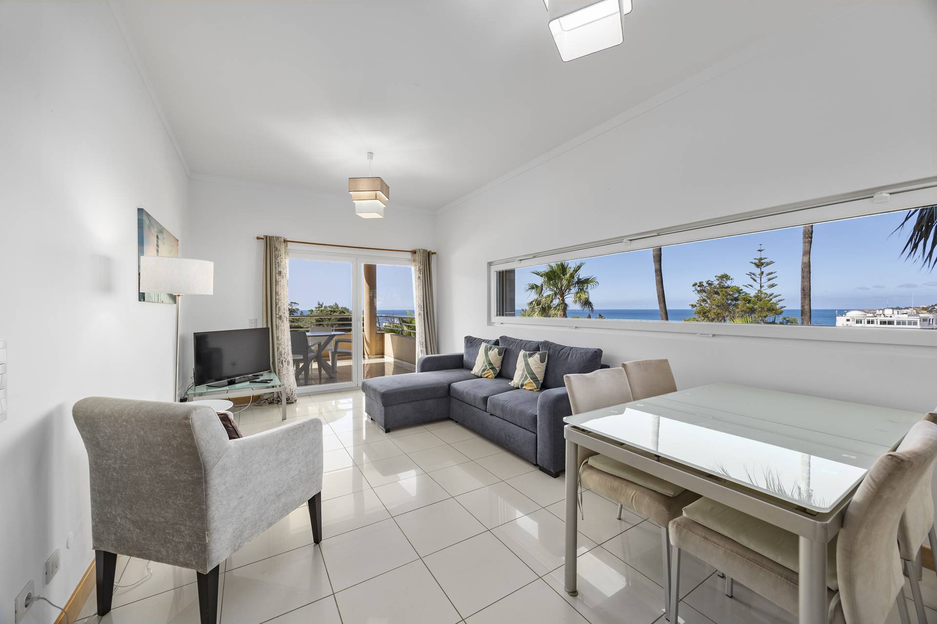 Living area with corner sofa, TV, and balcony access