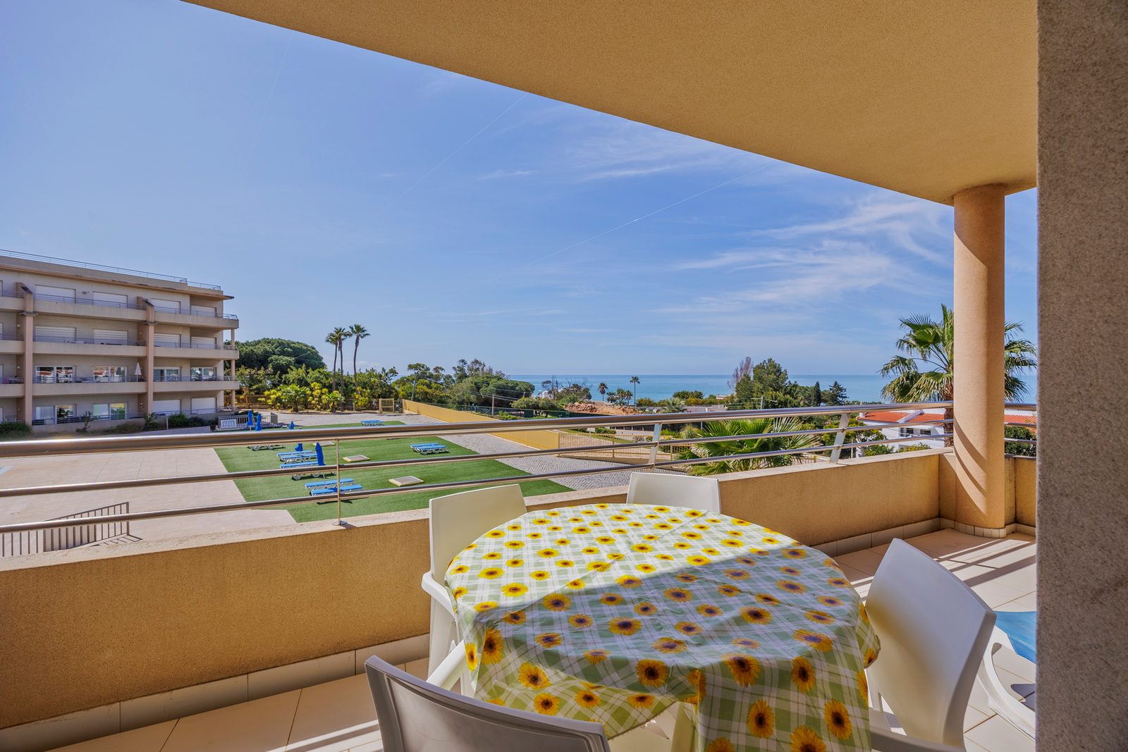 Balcony with dining table, chairs, and view over the pool and building