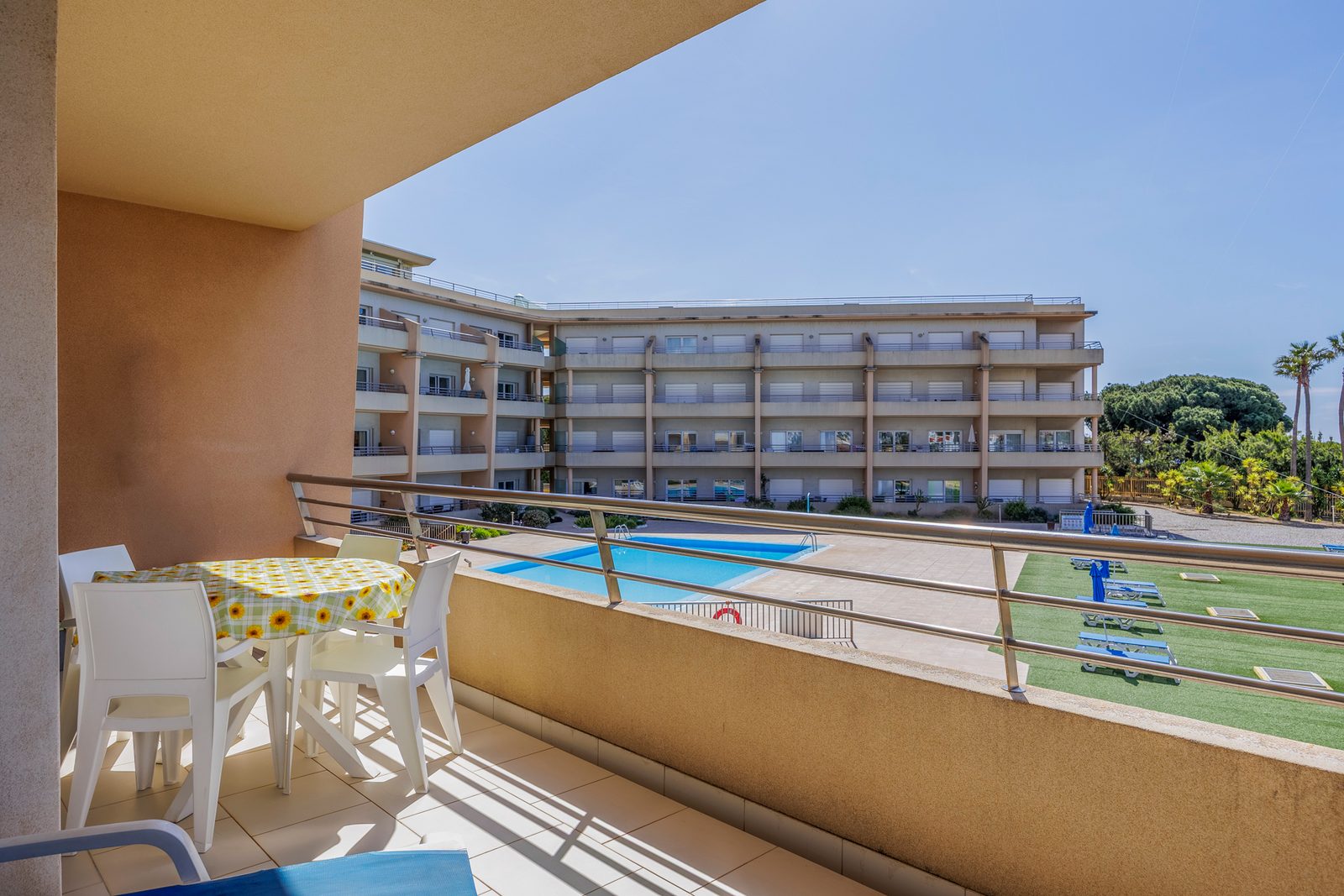 Balcony with dining table and view over the lawn and pool