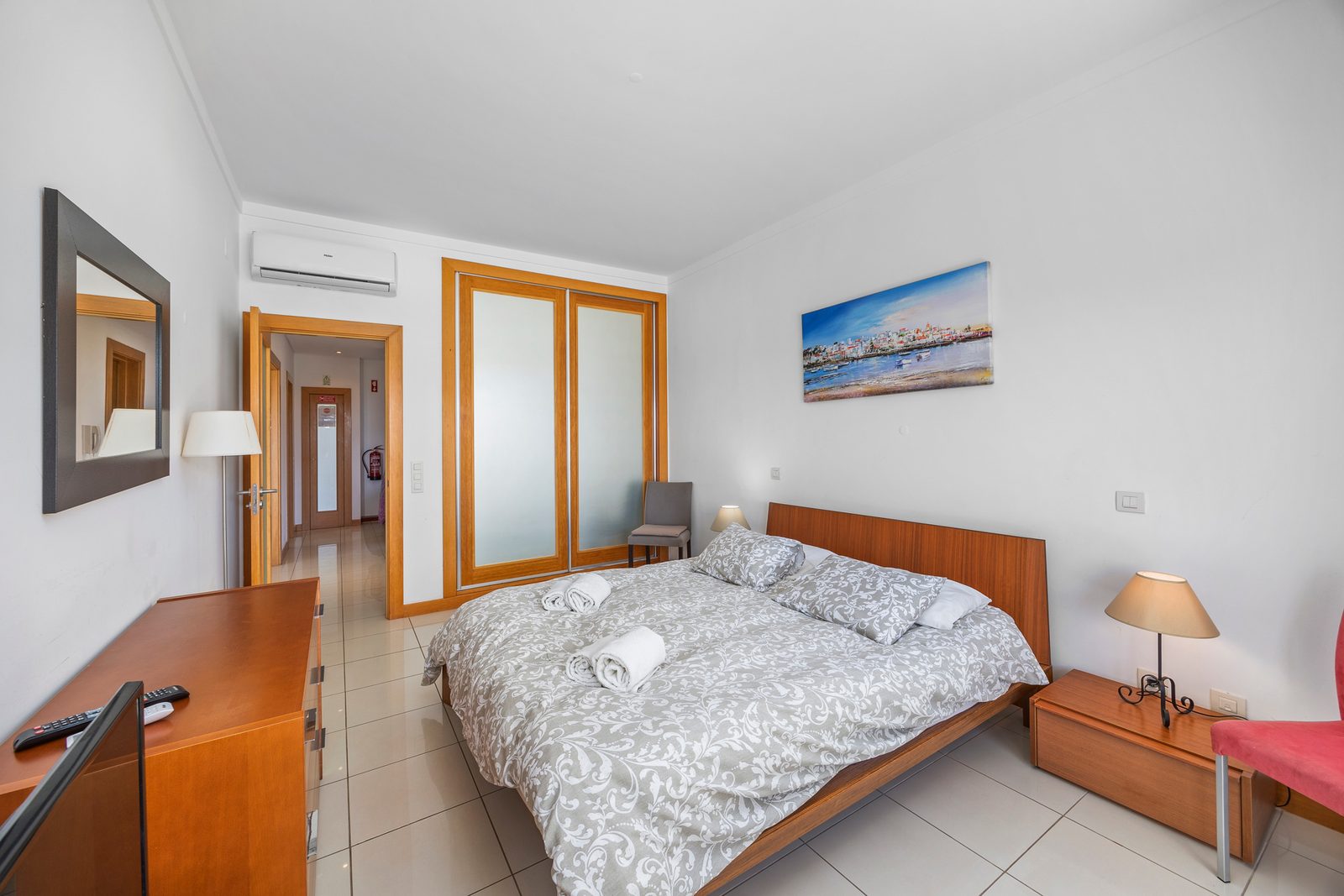 Bedroom with wall-mounted air conditioning and frosted glass wardrobe doors