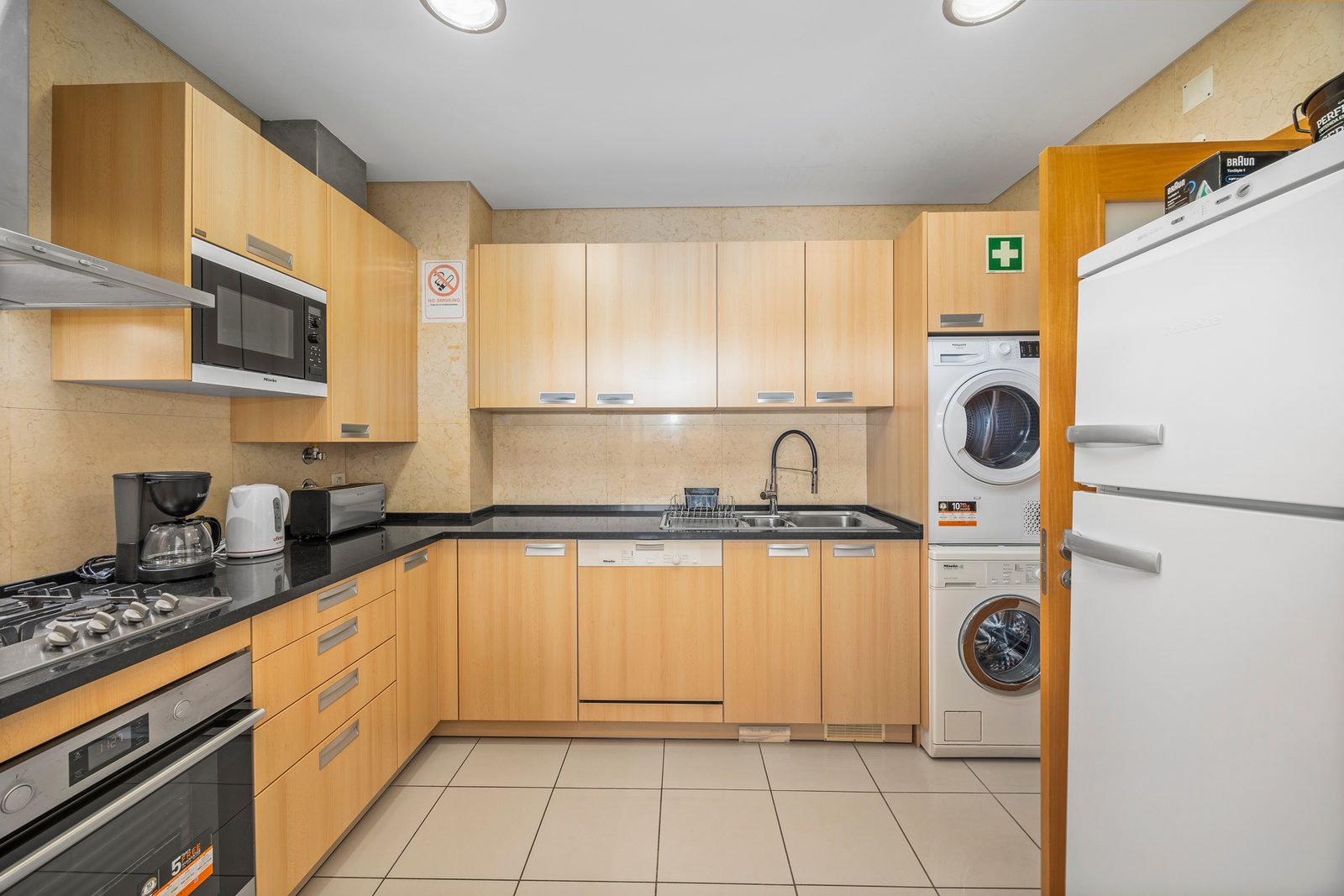 Kitchen with dishwasher, fridge, and stacked washer-dryer