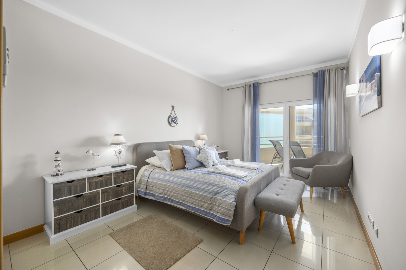 Bedroom with chest of drawers, seating bench, and balcony access